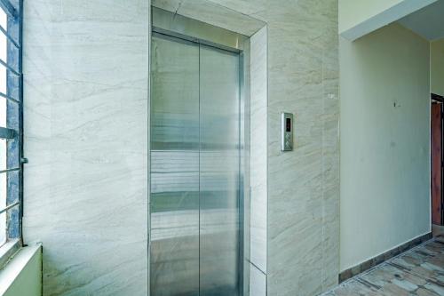 une porte de douche en verre sur un mur dans l'établissement Hotel O Thanisandra Railway Station Formerly Urban Drift, à Yelahanka