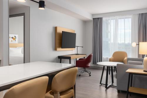 a room with a table and chairs and a tv at Staybridge Suites Montreal Airport - St-Laurent by IHG in Montréal