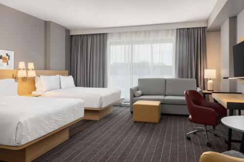 a hotel room with two beds and a couch at Staybridge Suites Montreal Airport - St-Laurent by IHG in Montréal