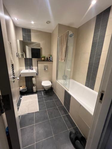 a bathroom with a toilet and a shower and a sink at Your Private Apartment in Vibrant Wembley! in London