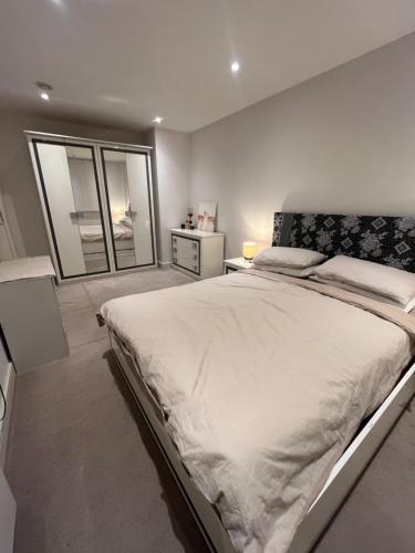 a white bedroom with a large bed and a window at Your Private Apartment in Vibrant Wembley! in London