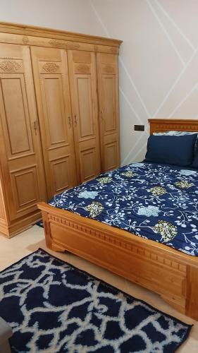 Un dormitorio con una cama y armarios de madera y una alfombra. en Appartement, en Chichaoua