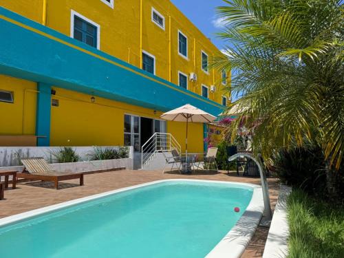 a swimming pool in front of a yellow building at Pousada Serra Bella in Tianguá