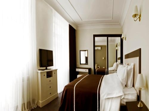 a hotel room with a bed and a television at Villa Rossa Hotel in Chişinău