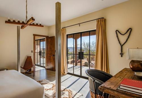 a bedroom with a bed and a desk and a window at Salt Pool - Sauna - Cold Plunge - Lux Desert Ranch in Pioneertown