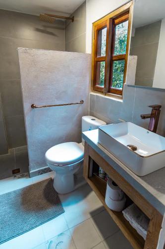 a bathroom with a white toilet and a sink at Palma Serena Finca Hotel in Santa Fe de Antioquia