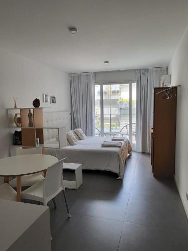 a white bedroom with a bed and a table at Dolce Apartment in Buenos Aires