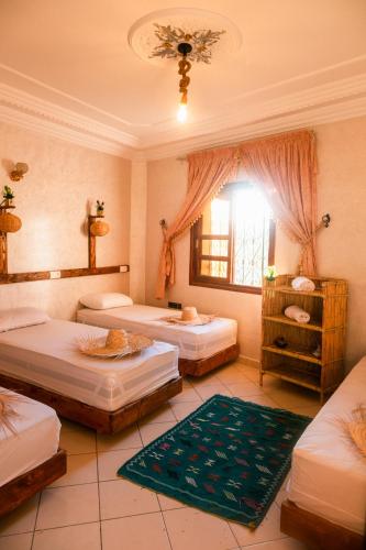 a room with three beds and a window at Surf Away Morocco in Agadir