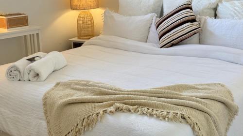 a large white bed with a blanket on it at Palacete Beach in Culburra Beach