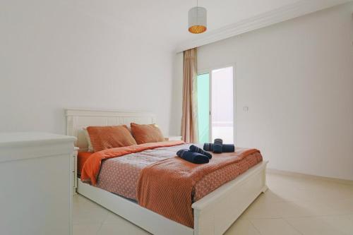 a white bedroom with a bed with two shoes on it at L'Andalou -3 bedrooms with Parking in Downtown in Kenitra