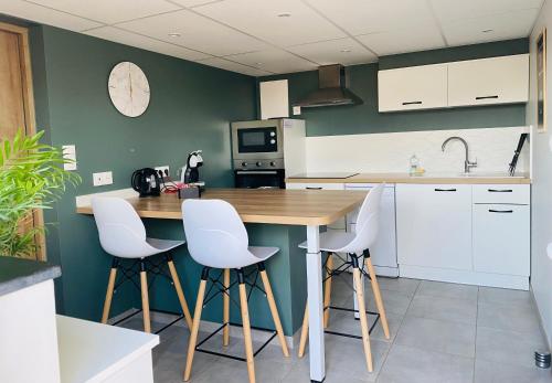 a kitchen with a wooden table and white stools at Élégant 2 pièces au calme, axe Metz-Luxembourg in La Celle-sous-Gouzon