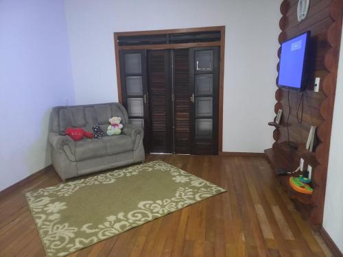 a living room with a chair and a flat screen tv at Sitio Daniela in São João Batista