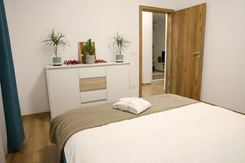 een slaapkamer met een wit bed en 2 potplanten bij Hushu Apartment in Giroc