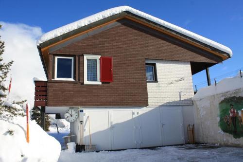 a house with a white fence in the snow at Casa Uccello in Wildhaus