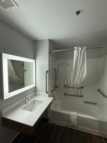 a bathroom with a sink and a shower with a mirror at Microtel Inn and Suites Baton Rouge Airport in Baton Rouge