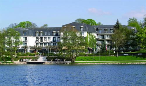 a large building next to a large body of water at Hotel Dieksee - Collection by Ligula in Malente