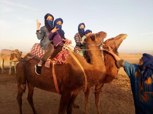 a group of people riding on the back of a camel at LA HACIENDA Agafay Desert 