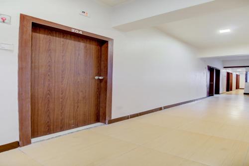 a hallway with a wooden door in a room at Hotel O Della Comforts in Ambernath
