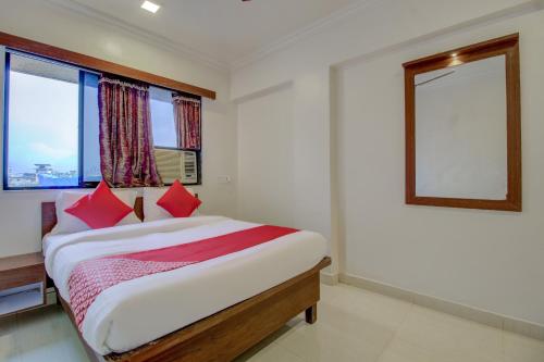 a bedroom with a bed with red pillows and a window at Hotel O Della Comforts in Ambernath