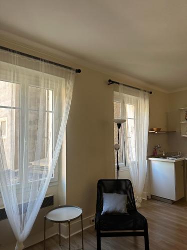 een woonkamer met een stoel en 2 ramen bij Studio Le Clocher in Saint-Étienne-de-Tinée