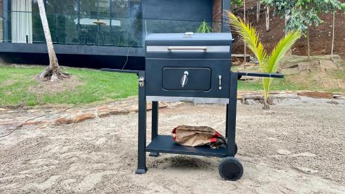 un barbecue bleu avec un sac posé au sol dans l'établissement Chalé com banheira, piscina e cachoeira privativa, à Taubaté