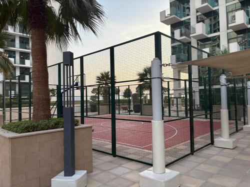 een tennisbaan achter een hek met een net bij Deluxe studio water front in Dubai