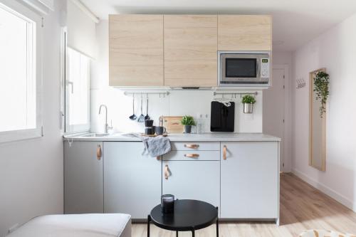 a small kitchen with white cabinets and a table at Charming Madrid lofts in Madrid