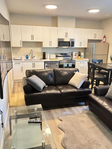 a living room with a leather couch and a kitchen at Prince George Cozy Suite in Prince George