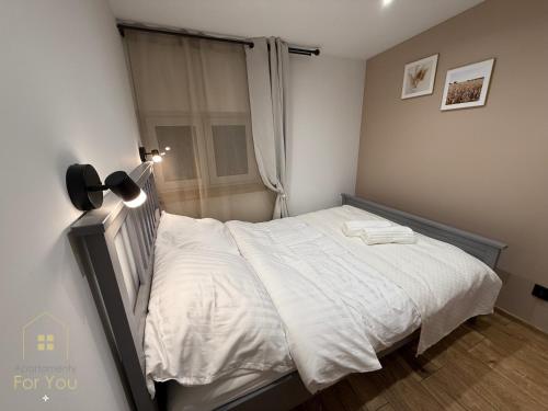 ビストシツァ・クウォツカにあるApartamenty For Youの白いシーツと窓のあるベッドのある寝室