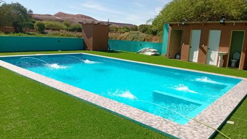 a swimming pool in a yard with grass at Hostal Ribera de Quitor in San Pedro de Atacama