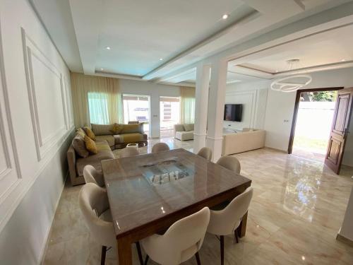 un salon avec une table et des chaises en bois dans l'établissement Villa H modern living steps from the beach, à Temara