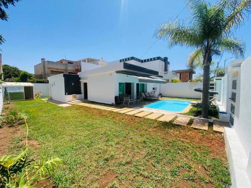 une maison avec une piscine et une cour dans l'établissement Villa H modern living steps from the beach, à Temara