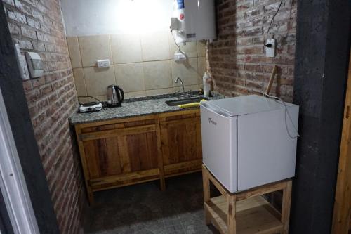a small kitchen with a sink and a refrigerator at Cabañas La Sarita in La Consulta