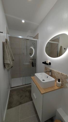 a bathroom with a sink and a shower with a mirror at L'alcôve - appartement moderne et spacieux - proche gare - centre historique - WiFi - Clim in Béziers