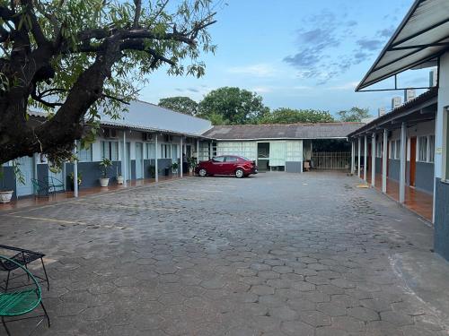 a red car parked in a parking lot between buildings at Hotel Lupinetti in Jaciara