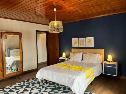 a bedroom with a large bed and a blue wall at Casa Três Campos, Povoação in Povoação