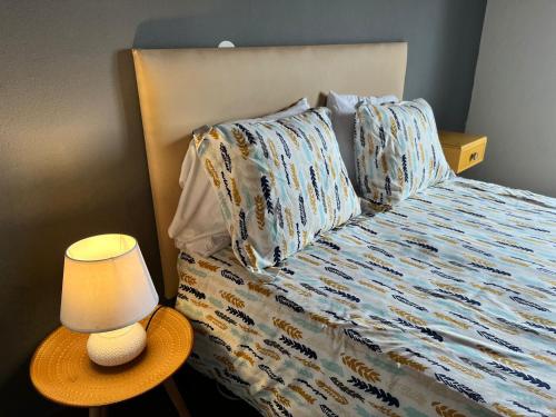 a bed with pillows and a lamp on a table at Casa Três Campos, Povoação in Povoação