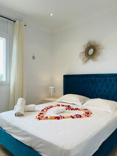 a bed with a blue headboard with a flower arrangement on it at Maison Douceur in Dar el Ouzir