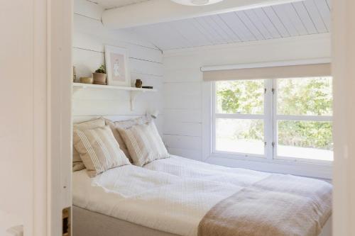 une chambre blanche avec un lit et une fenêtre dans l'établissement Hear The Sea From Log Cabin In Gilleleje, à Gilleleje