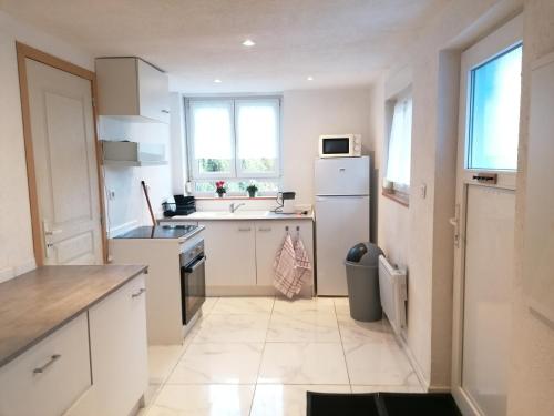 a kitchen with white cabinets and a white refrigerator at Appartement T2 44 m2 in Kesseldorf