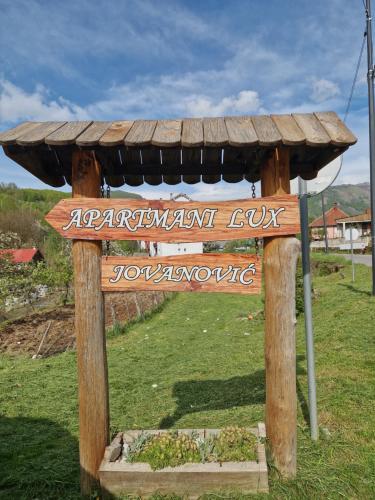 un panneau en bois dans un champ avec un toit dans l'établissement Apartmani LUX, à Kolašin