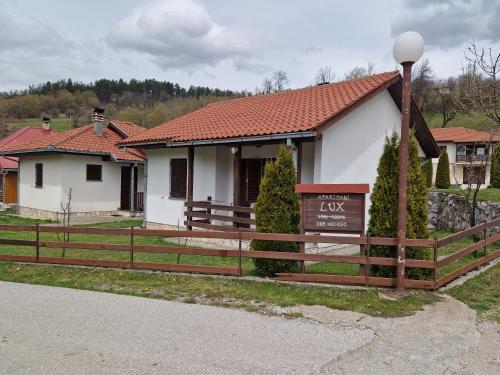 une maison avec une clôture et un panneau devant dans l'établissement Apartmani LUX, à Kolašin