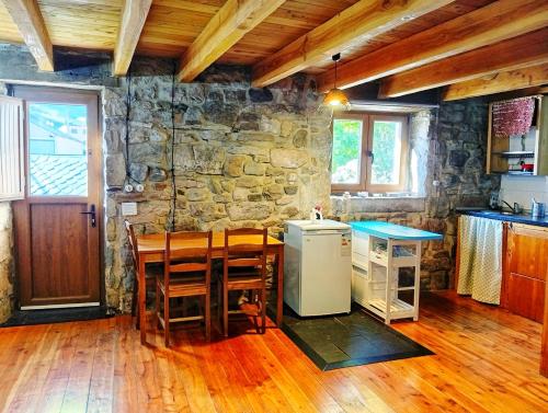a kitchen with a table and a stone wall at Casa La Farrapona de Babia in Torrestío