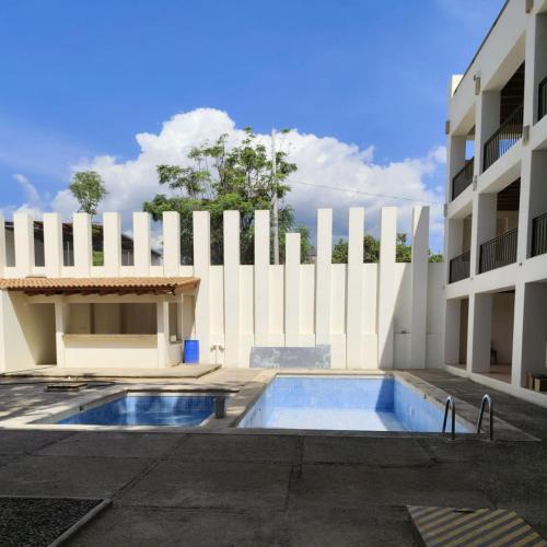 a building with a white fence and a swimming pool at Hotel Azul Agave Oaxaca in Yelateni