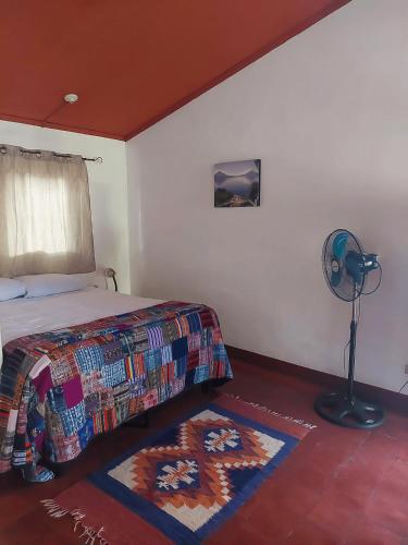 a bedroom with a bed and a fan and a rug at El Aguacatal in Panajachel