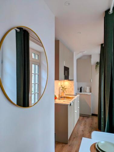 a mirror on a wall in a kitchen with a sink at Studio cosy proche étang et commerces in Saint-Aubin-du-Cormier