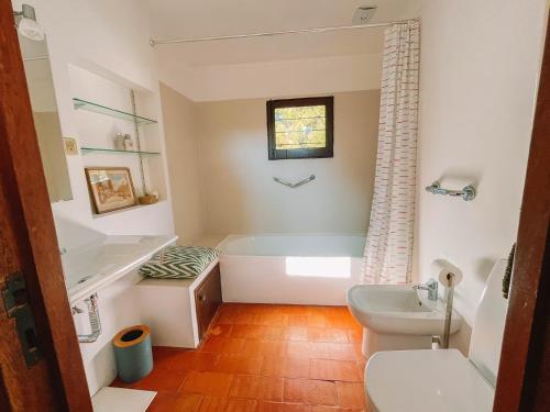 a bathroom with a tub and a toilet and a sink at Camarinhas House in Moledo