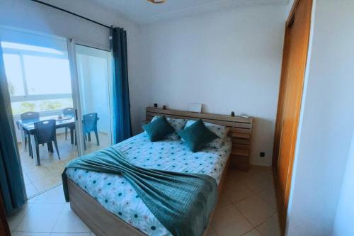 a bedroom with a bed and a table and a window at Marina Golf location Appartement Climatisé Wifi Piscines Parking Gratuit in Asilah