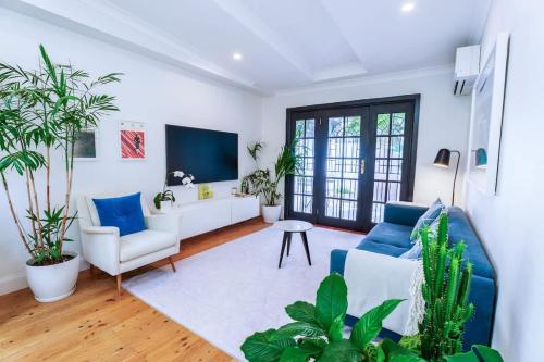 een woonkamer met blauwe en witte meubels en planten bij Surry Hills Cottage in Sydney