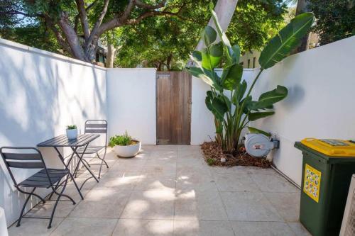 een terras met een tafel, stoelen en een hek bij Surry Hills Cottage in Sydney